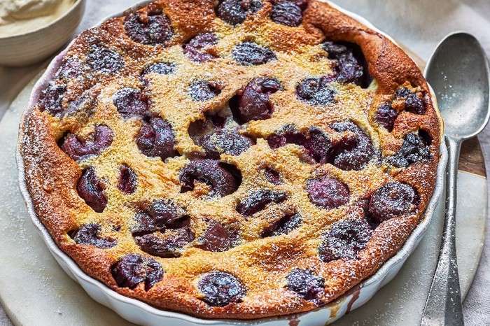 A large cherry clafoutis in a round dish with a spoon