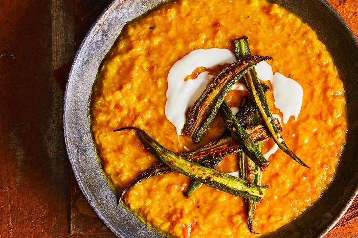 A bowl of orange dhal topped with crisp fried okra
