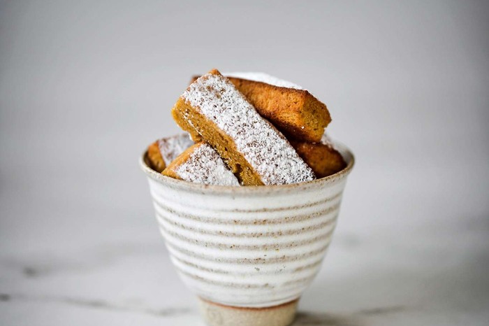A small bowl of financiers against a grey background