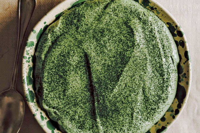 A bright green tiramisu on a circular serving plate