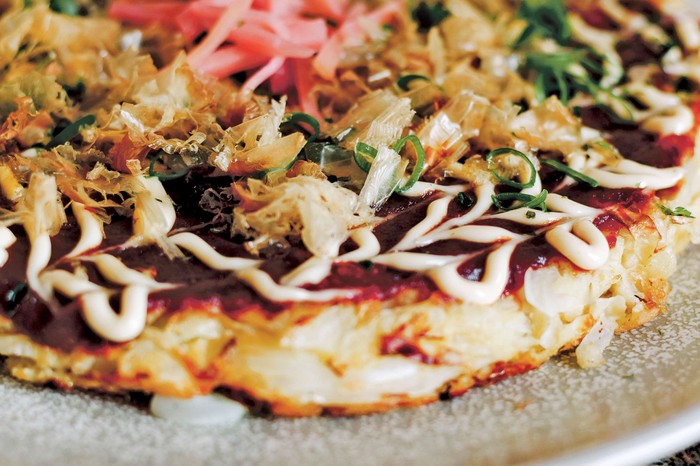A Japanese-style cabbage and cheese okonomiyaki on a small grey plate