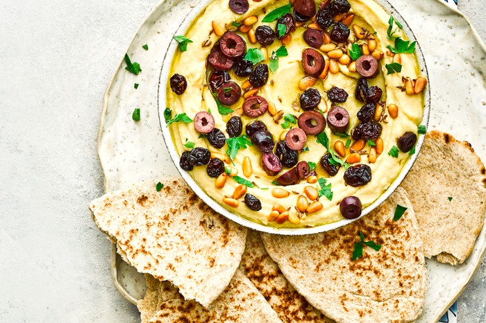 Easy Hummus Recipe Topped with Pine Nuts, Raisins and Olives