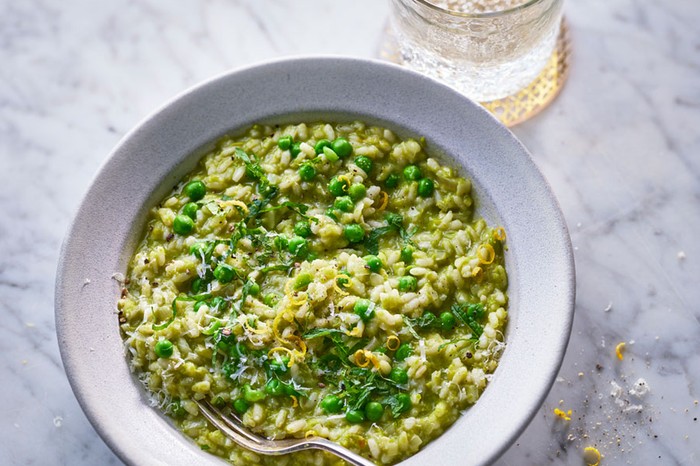 Bowl of pea risotto next to a glass of water